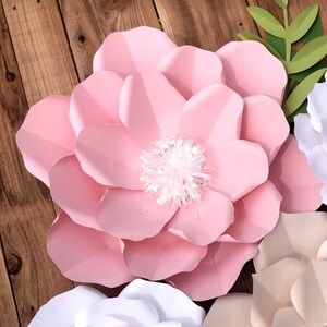 May include: A large, pink paper flower with a sparkly center. The flower is made of multiple layers of paper and has a delicate, feminine look.