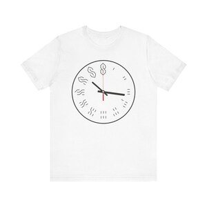Könnte beinhalten: Weißes T-Shirt mit einem schwarz-weißen Uhrendesign, das den Buchstaben 'S' in verschiedenen Stilen wiederholt. Die Uhrzeiger sind schwarz und rot.