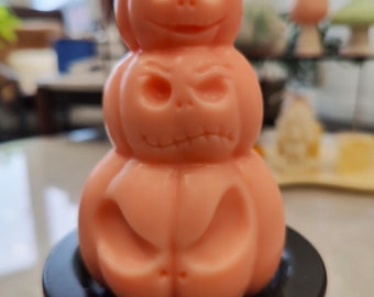 Könnte beinhalten: Ein Stapel aus drei rosa Kürbiskerzen mit Kürbisgesichtern. Die Kerzen stehen auf einem schwarzen Kerzenhalter. Das Etikett auf der obersten Kerze lautet "Just For You".