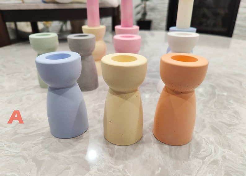 May include: A set of ten candle holders in various pastel colors, including light blue, pink, yellow, and orange. The candle holders are made of a textured material and have a simple, modern design.