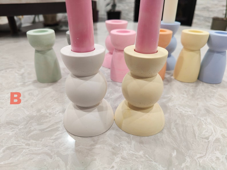May include: A set of six candle holders in various pastel colors, including light green, pink, yellow, and blue. The candle holders are made of ceramic and have a simple, modern design.