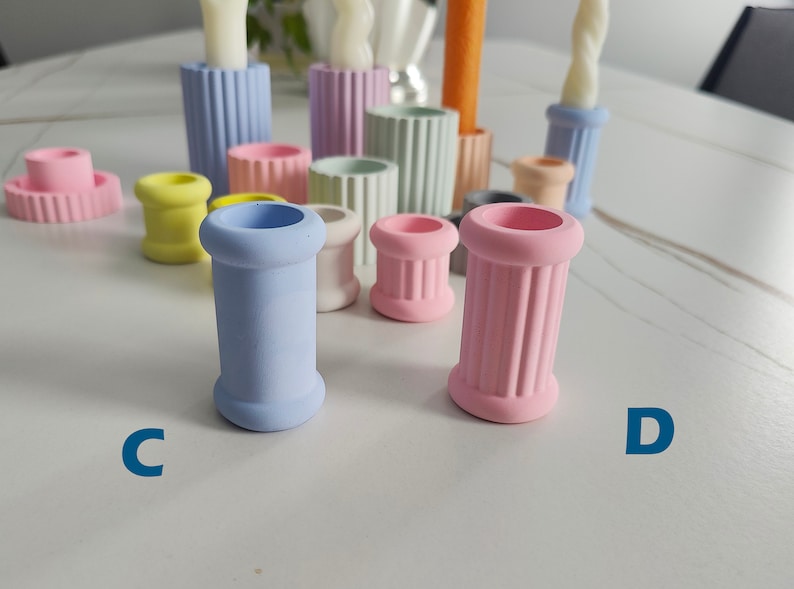 May include: A set of 10 colorful candle holders in various pastel colors, including light blue, pink, yellow, and green. The holders are made of ceramic and have a fluted design. The holders are arranged in a group on a white surface.