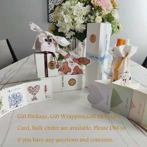 May include: A table with a variety of gift wrapping supplies, including boxes, bags, tissue paper, and cards. The supplies are decorated with a cute bear design and the text "Just for you".