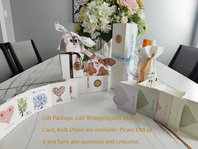 May include: A table with a variety of gift wrapping supplies, including boxes, bags, tissue paper, and cards. The supplies are decorated with a cute bear design and the text "Just for you".