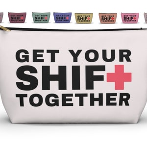 May include: White canvas zippered pouch with a black and pink graphic that says "GET YOUR SHIF+ TOGETHER".