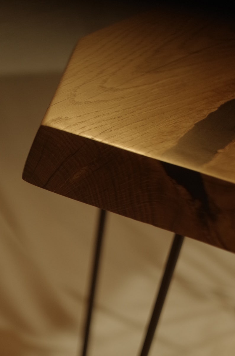 Op de afbeelding: Een close-up van een houten tafelblad met een live edge. De tafel heeft zwarte hairpin poten.