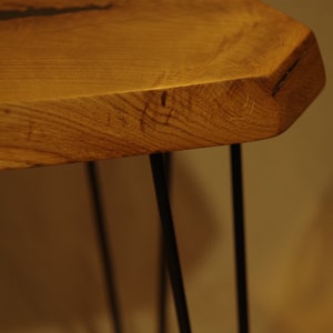 Op de afbeelding: Een houten tafel met een live edge blad en zwarte haarspeldpoten. De tafel is gemaakt van natuurlijk hout en heeft een rustieke uitstraling.