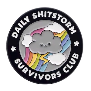 May include: A round, black enamel pin with the text "DAILY SHITSTORM SURVIVORS CLUB" in white. The pin features a gray cloud with a sad face, a rainbow, lightning, and white clouds.