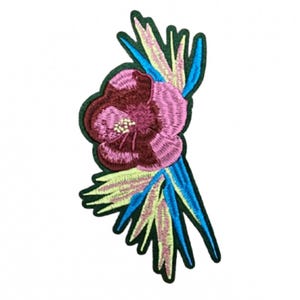 May include: Embroidered floral patch featuring a burgundy and pink flower with yellow and blue accents. The patch has a dark green border and is designed to be sewn or ironed onto fabric. Ideal for adding a decorative touch to clothing or accessories.