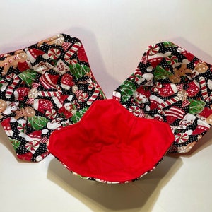 May include: Three red and black Christmas-themed fabric bowl cozies. The cozies are lined with red fabric and feature a pattern of gingerbread men, candy canes, and Christmas trees.