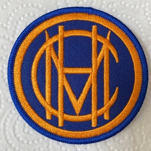 May include: A blue and gold embroidered patch with the letters "FC" in a circle.