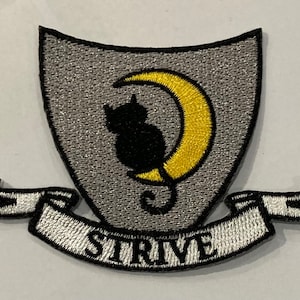 May include: A grey embroidered patch featuring a black cat sitting on a yellow crescent moon. The patch has a white banner with the word "STRIVE" embroidered in black.