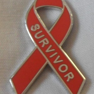 Puede incluir: Un pin de cinta roja con la palabra "SURVIVOR" escrita en letras blancas.