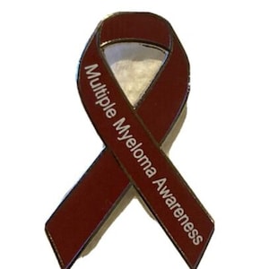 May include: A red ribbon pin with the words "Multiple Myeloma Awareness" printed in white.