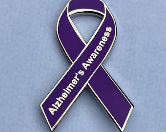 May include: Purple ribbon pin with silver trim and the words "Alzheimer's Awareness" printed on it.