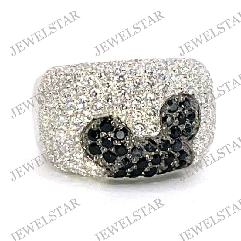 May include: A silver ring with a black and white Mickey Mouse design. The ring is covered in small, sparkling stones.