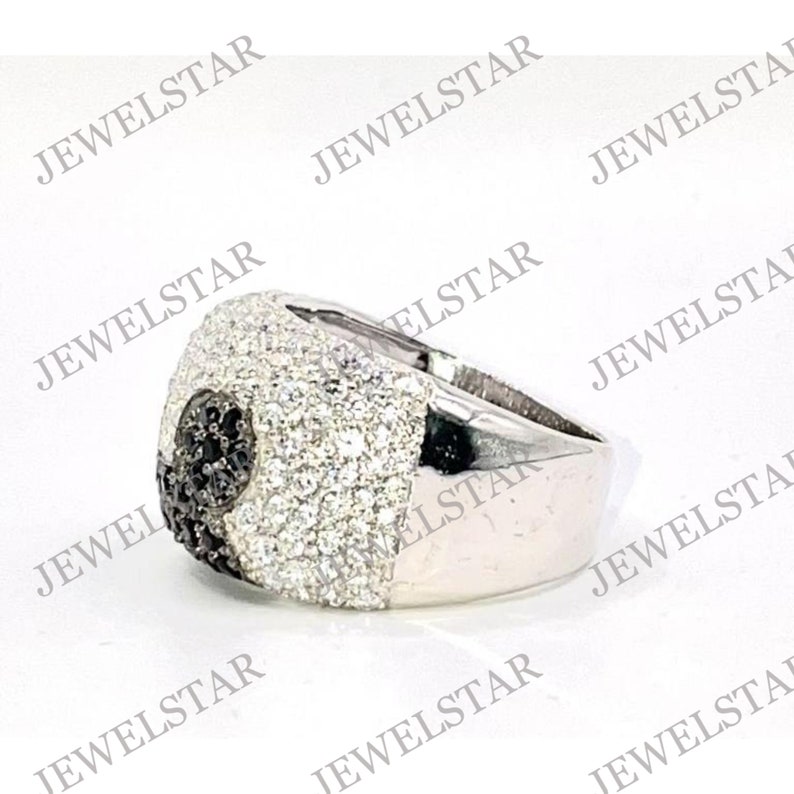 May include: A silver ring with a black and white stone setting. The ring is set with small, round stones that cover the entire surface of the ring.
