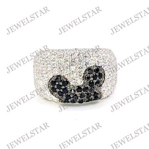 May include: A silver ring with a black and white Mickey Mouse design. The ring is covered in small, sparkling stones.