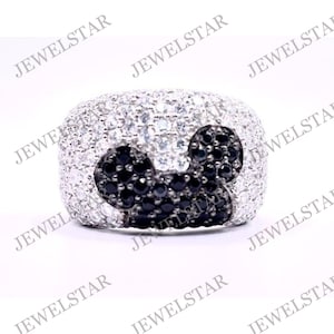 May include: A silver ring with a black and white Mickey Mouse design. The ring is set with small black and white stones.