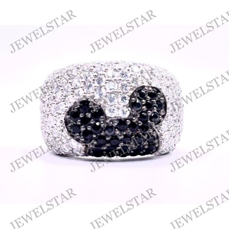 May include: A silver ring with a black and white Mickey Mouse design. The ring is set with small black and white stones.