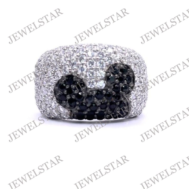 May include: A silver ring with a black and white Mickey Mouse design. The ring is set with small black and white stones.
