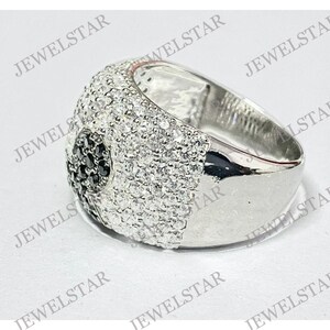 May include: A silver ring with a black and white stone design. The ring is set with small, round stones that create a textured look. The ring is a statement piece that would be perfect for a special occasion.