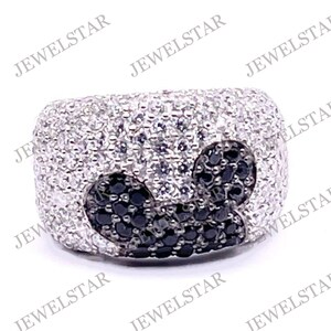 May include: A silver ring with a black and white heart design. The ring is set with small, sparkling stones.