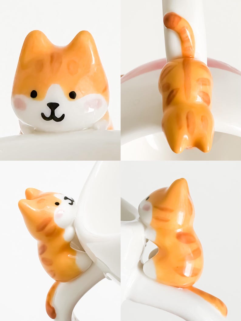 May include: A white ceramic mug with a cute orange and white cat figurine attached to the handle. The cat is in a sitting position with its tail wrapped around the handle.
