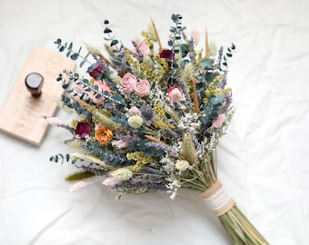 May include: A dried flower bouquet with pink, orange, and purple flowers, green eucalyptus leaves, and dried grasses. The bouquet is tied with a brown ribbon.