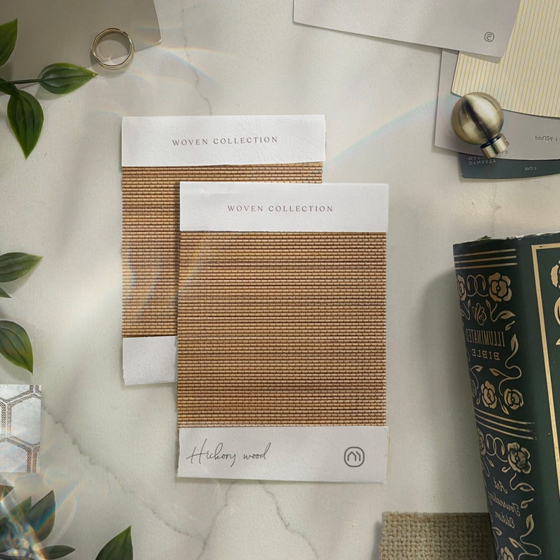 K&ouml;nnte beinhalten: Zwei Stoffmuster aus gewebtem Stoff mit dem Text "WOVEN COLLECTION" und "Hickory Wood". Die Muster sind hellbraun mit einer gewebten Textur.