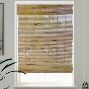 May include: Natural woven bamboo window blinds in a light brown colour. The blinds are raised to reveal the white window frame behind them.