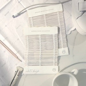 May include: Two white wood samples with the text "Modern Wood Collection" and "White Dough". The samples are made of thin, woven strips of wood.