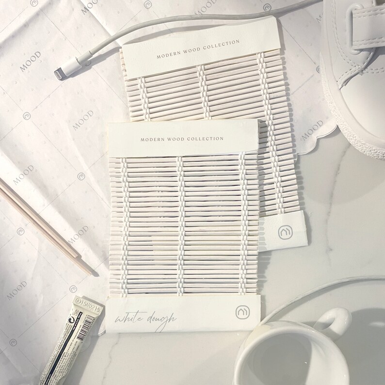 May include: Two white wood samples with the text "Modern Wood Collection" and "White Dough". The samples are made of thin, woven strips of wood.
