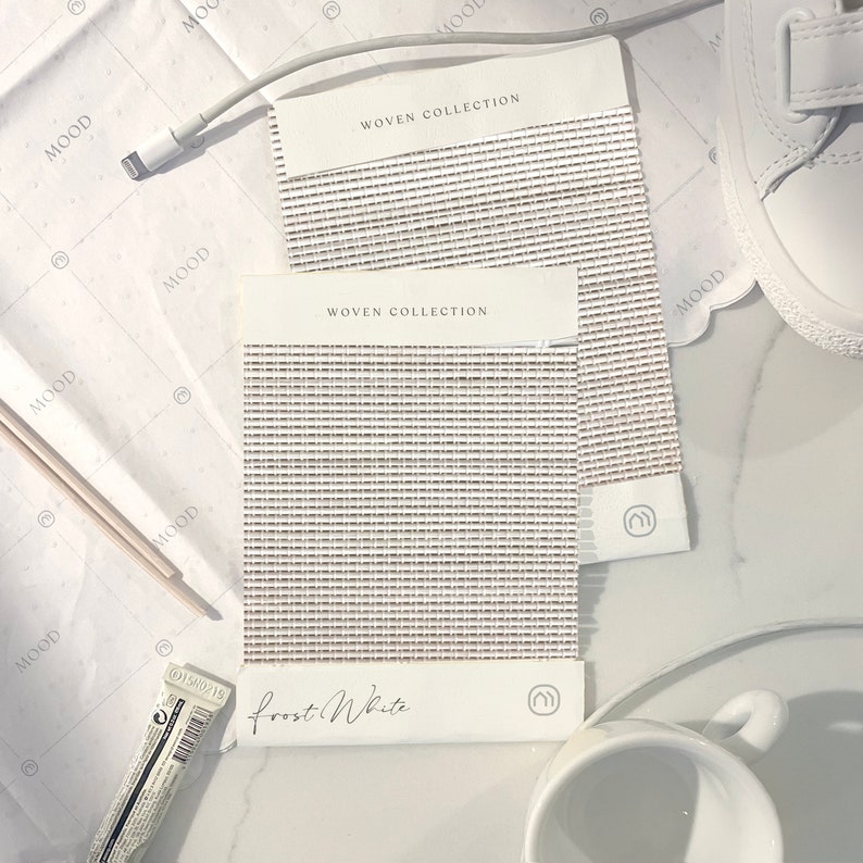 K&ouml;nnte beinhalten: Zwei Stoffmuster aus gewebtem Stoff in hellbeige mit einem dezenten Muster. Die Stoffmuster sind mit "WOVEN COLLECTION" und "Frost White" beschriftet.