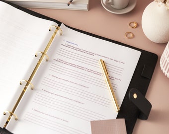 Könnte beinhalten: Ein schwarzer Lederordner mit goldfarbenen Ringen und einem Stift. Der Ordner ist zu einem Arbeitsblatt mit dem Text "C. Product/Service" geöffnet. Eine Tasse Kaffee, ein Buch und dekorative Gegenstände befinden sich auf der rosa Oberfläche.