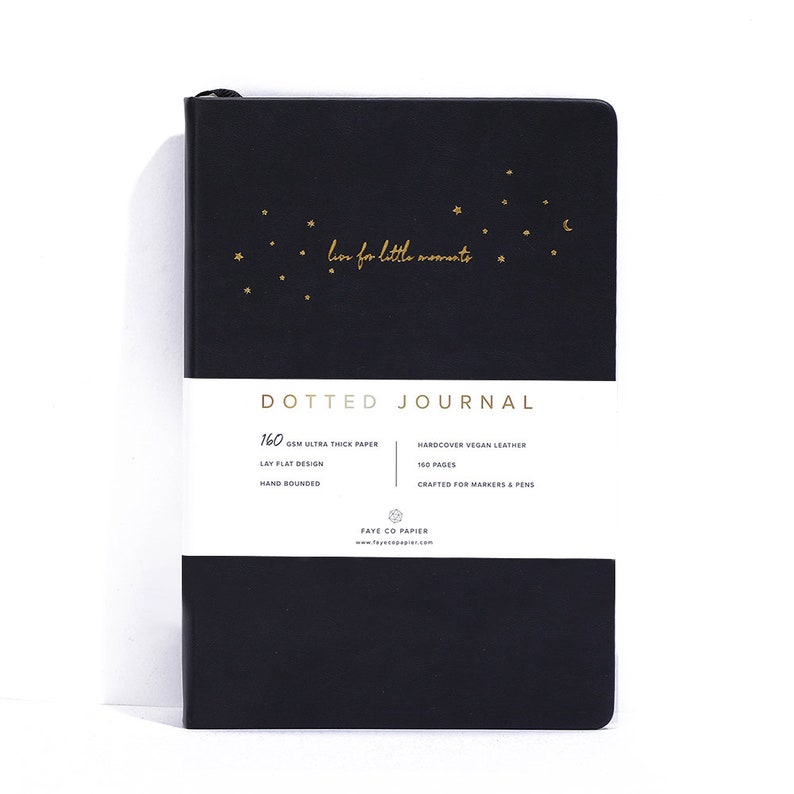 K&ouml;nnte beinhalten: Schwarzes gepunktetes Notizbuch mit goldenen Sternen und dem Schriftzug "live for little moments". Das Notizbuch hat 160 g/m&sup2; ultra-dickes Papier, ein flaches Design und ist handgebunden. Es hat einen Einband aus veganem Leder und ist f&uuml;r Marker und Stifte geeignet.