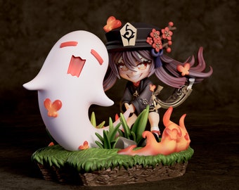 May include: A small, white ghost figurine with a red mouth and black eyes, standing next to a small, dark-haired anime character figurine wearing a black and red outfit with a red flower crown. The figurines are standing on a green and brown base.