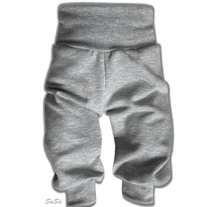 Peut inclure: Un pantalon de bébé gris avec une taille haute et pliée et des poignets resserrés. Le pantalon est fait d'un tissu doux et extensible, conçu pour le confort et les mouvements. Le pantalon est présenté sur fond blanc.
