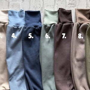 May include: A collection of ten ribbed long-sleeve shirts in various colors, numbered one through ten. The colors include purple, light pink, beige, light blue, dark blue, sage green, dark brown, taupe, olive green, and mustard yellow.