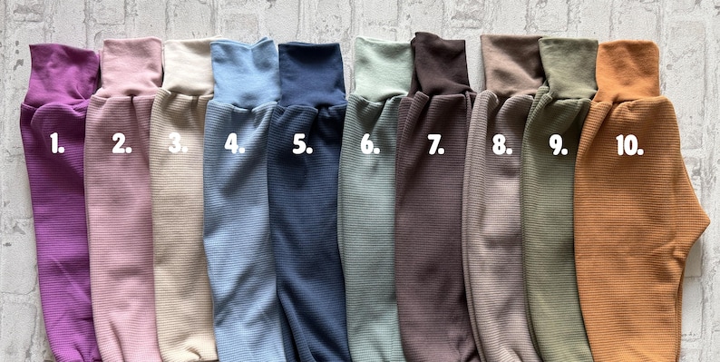 May include: A collection of ten ribbed long-sleeve shirts in various colors, numbered one through ten. The colors include purple, light pink, beige, light blue, dark blue, sage green, dark brown, taupe, olive green, and mustard yellow.