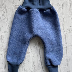 K&ouml;nnte beinhalten: Blaue Babyhose mit hohem, dunkelblauem Bund und B&uuml;ndchen. Die Hose ist aus einem weichen, strukturierten Stoff gefertigt. Das Design hat einen runden Sitz und eine bequeme Passform, geeignet f&uuml;r Babys und Kleinkinder.