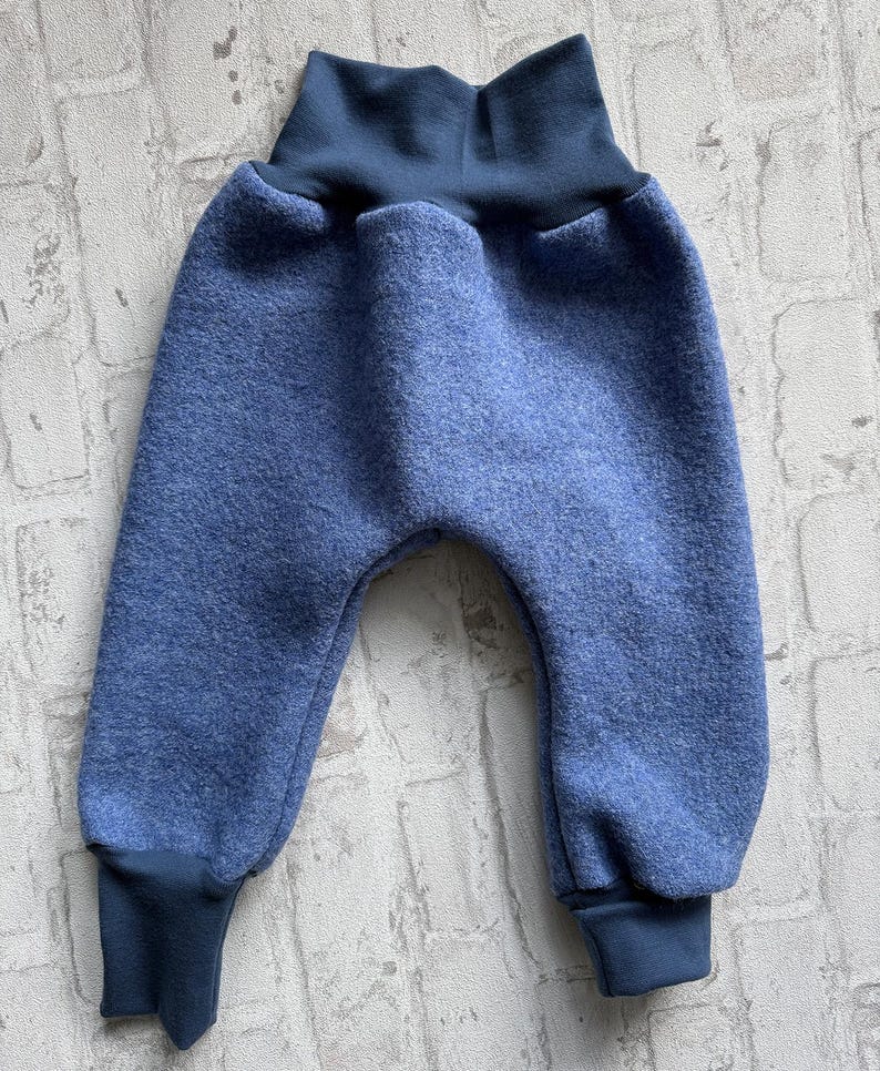 K&ouml;nnte beinhalten: Blaue Babyhose mit hohem, dunkelblauem Bund und B&uuml;ndchen. Die Hose ist aus einem weichen, strukturierten Stoff gefertigt. Das Design hat einen runden Sitz und eine bequeme Passform, geeignet f&uuml;r Babys und Kleinkinder.
