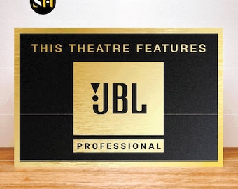 May include: Gold plaque with black text that reads "This theatre features JBL Professional". The JBL logo is in a gold square.
