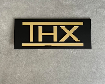 May include: A black rectangular sign with the word "THX" in gold letters.