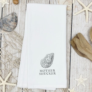 May include: White kitchen towel with a black and white illustration of an oyster and the text "Mother Shucker".