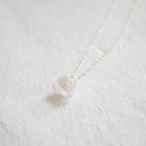 May include: A delicate white flower pendant necklace with a small pearl accent. The necklace is made of silver chain and features a simple, elegant design.