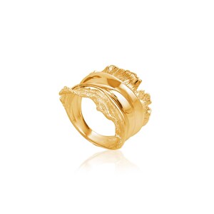 Könnte beinhalten: Ein goldfarbener Ring mit einem strukturierten, organischen Design. Der Ring ist breit und hat eine einzigartige, asymmetrische Form.