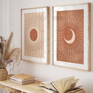 Puede incluir: Dos impresiones enmarcadas con un dise&ntilde;o minimalista. Las impresiones presentan un sol y una luna creciente con l&iacute;neas radiantes de color naranja quemado sobre un fondo crema.