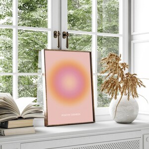 May include: A framed print with a pink and orange gradient circle design. The text "POSITIV DENKEN" is printed in white at the bottom of the print.