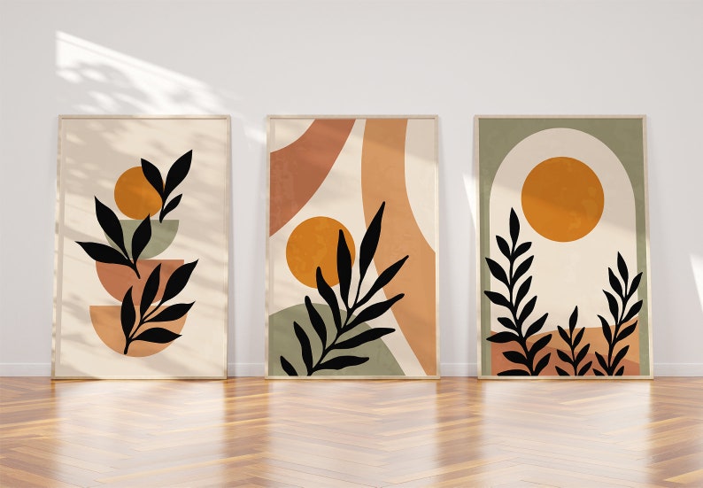 Op de afbeelding: Drie abstracte kunstprints met een minimalistisch ontwerp met zwarte silhouetten van bladeren en takken tegen een achtergrond van beige, oranje, groene en bruine geometrische vormen.